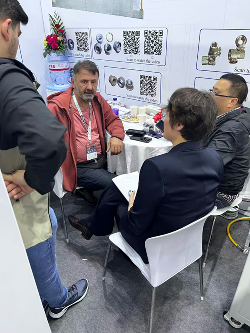 标题: Qingdao C&C team discussing valve and fitting machining requirements with a visitor at CCMT 2026 - 说明 Qingdao C&C team discussing valve and fitting machining requirements with a visitor at CCMT 2026
